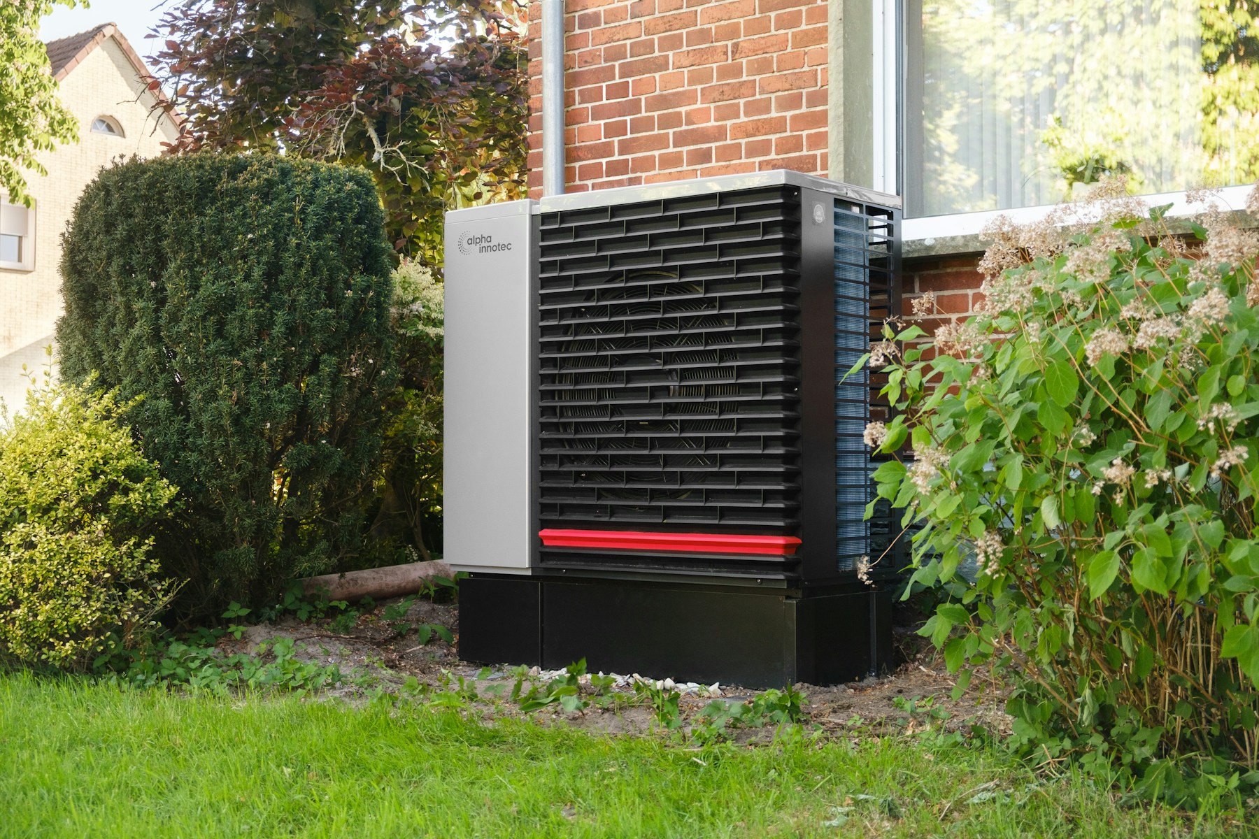 Modern outdoor heat pump unit installed beside a brick house